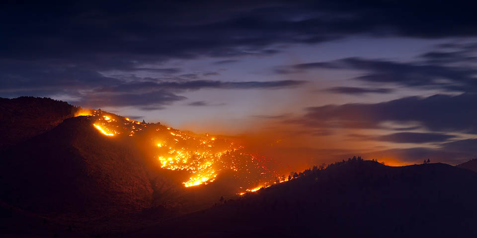 Wildfire burns against a dark blue sky