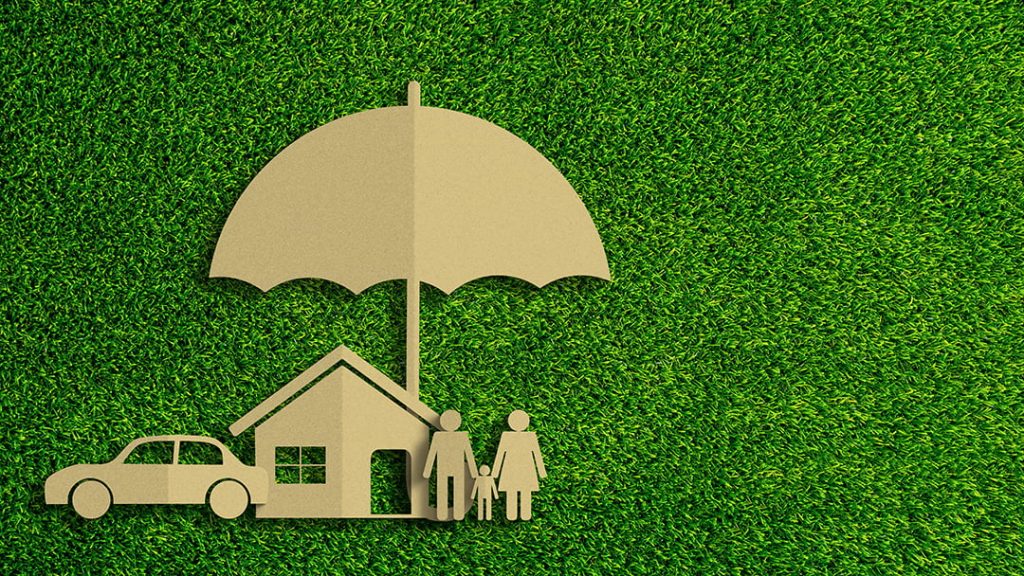 Kraft paper cutouts of a family, home, and car under a large umbrella set against a green grass background